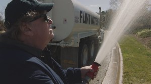 Michael Moore en action avec l'eau polluée de Flint. DR